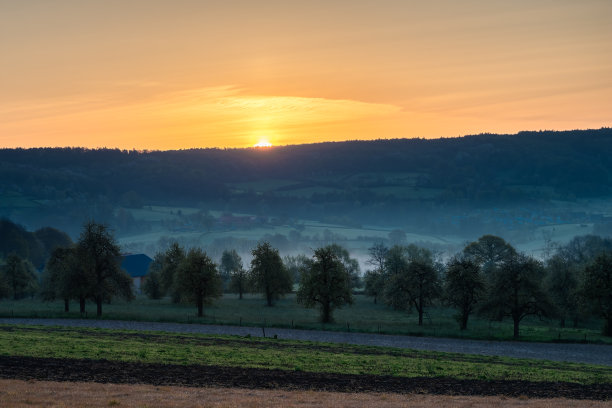 夏日清晨，五彩缤纷的日出，地面上有一点雾，在荷兰林堡的山坡上可以看到壮观的景色图片下载