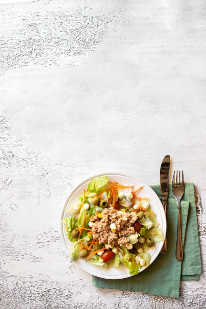白色混凝土背景上的金枪鱼沙拉，有生菜、西红柿、胡萝卜和玉米。本空间图片下载