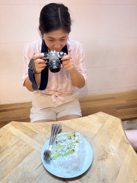 欧亚Z世代妇女用胶片相机拍摄蛋糕照片图片下载