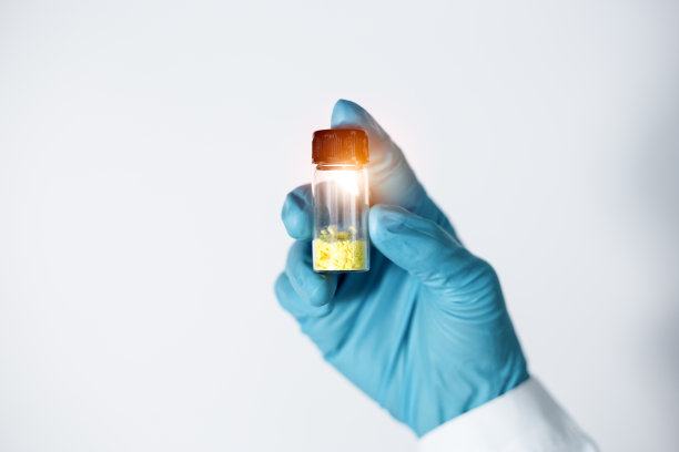 科学家的手特写显示了从实验室提取和分离的类黄酮化合物的小玻璃瓶中的淡黄色固体。图片下载