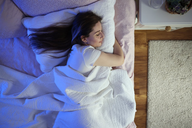 宁静美丽的女人睡觉，手放在枕头上的脸颊下图片下载