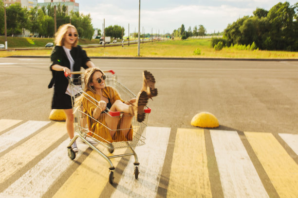 两个年轻的金发女孩在购物车里玩得很开心。时尚的女人图片下载