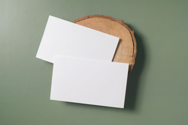 白色空白名片模型木制杯垫与绿色背景。模拟演示。图片下载