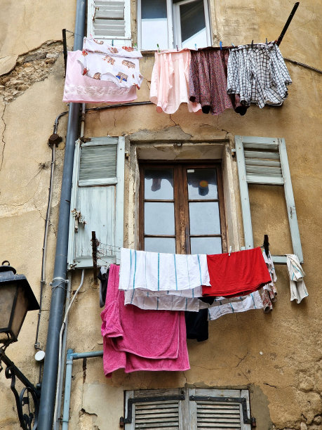 多种颜色的衣服挂在风化的窗台和木制百叶窗上晾干-法国，欧洲图片下载