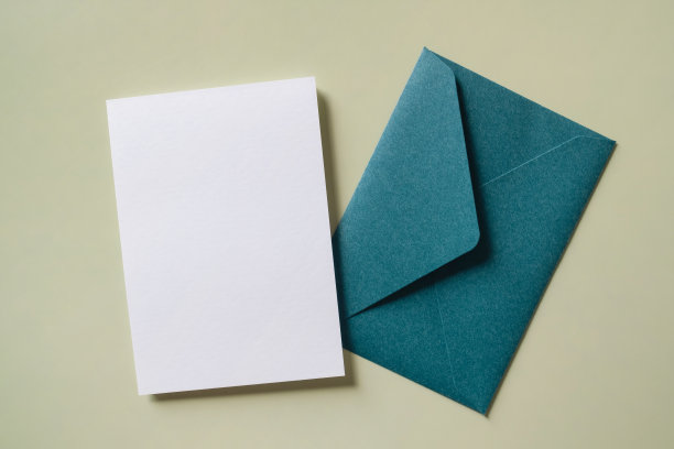 白色空白问候或邀请卡和绿色背景的信封。模拟演示。图片下载