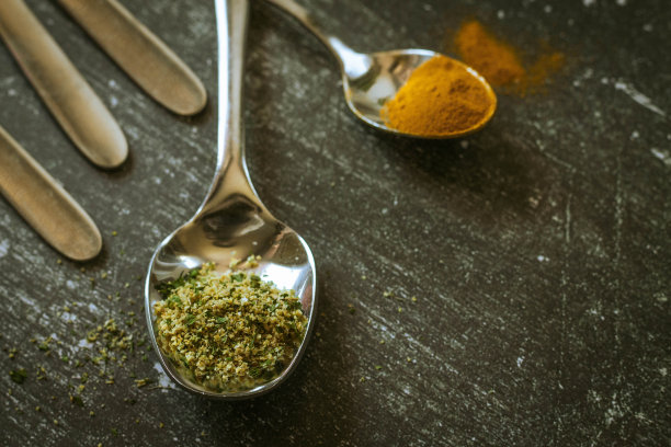 黑色背景上盛有香料和香草的勺子。食品和烹饪材料。图片下载