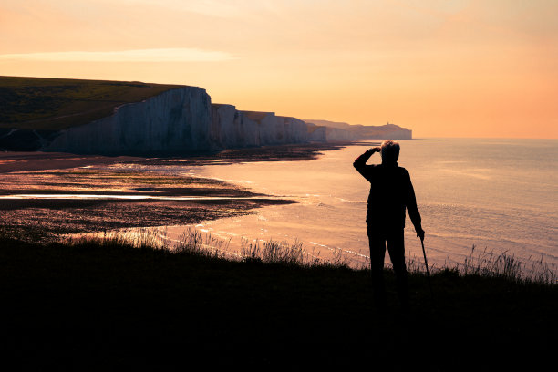 资深徒步旅行者在日落时观赏七姐妹悬崖和大海图片下载