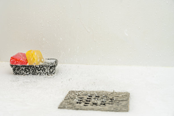 一些湿漉漉的红色和黄色的甘油肥皂条放在一个不锈钢水槽里，淋浴的水滴落在上面图片下载