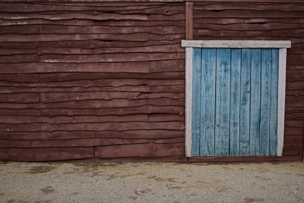 一堵由棕色木材制成的墙和一扇蓝色的门的细节图片下载