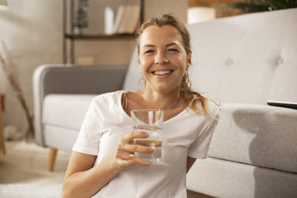 微笑的女人在喝水。图片下载