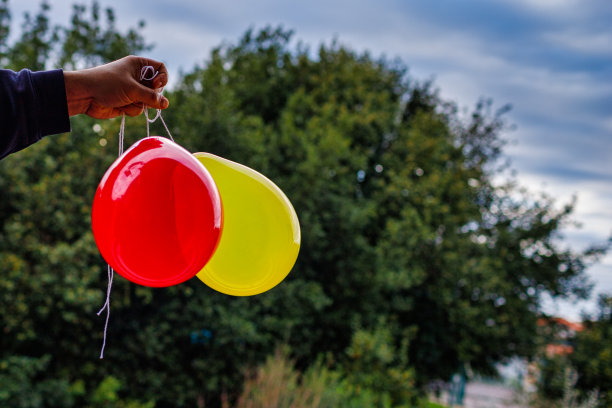 手里拿着红色、黄色的气球图片下载