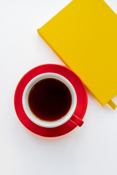 一个红色茶杯和一个黄色笔记本的俯视图。图片下载