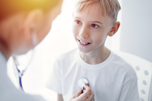 医生和快乐微笑的小男孩病人在诊所例行体检。医学、保健概念图片下载