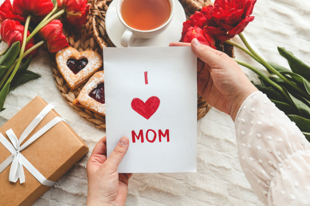 女人手里拿着一张精美的手绘母亲节贺卡，上面有红色的信封，卡片上有我爱你妈妈的字样图片下载
