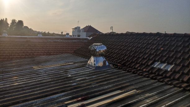 在屋顶顶部移动的用于热控制的屋顶通风机。暴露在午后阳光下的屋顶通风机图片下载