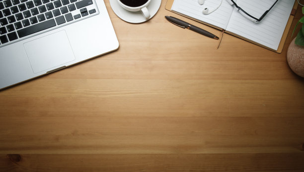 木制背景的笔记本电脑、咖啡杯、笔记本和眼镜。带复制空间的俯视图。图片下载