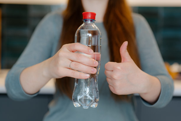 一个女人拿着一个装有清水的塑料瓶图片下载