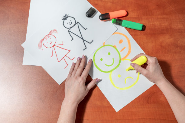 一个女人用毡尖笔在一张白纸上画着小男人。坐在桌子旁。从上面看图片下载