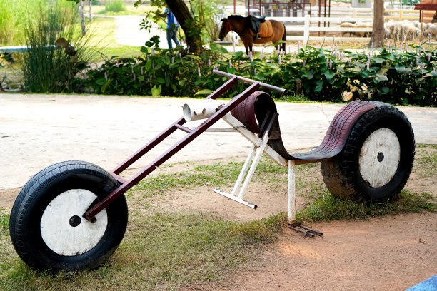 图为公园里一辆简单的老式儿童摩托车，由大轮胎和废金属制成。图片下载