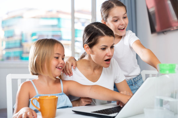 热情的姐妹们和妈妈一起在笔记本电脑上看有趣的东西图片下载