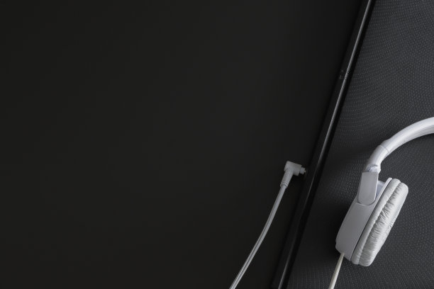 有文字位置的水平横幅——白色耳机和部分笔记本在黑色背景上。图片下载