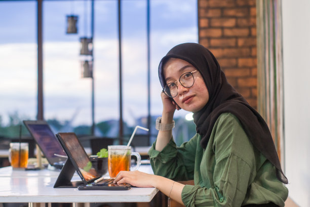 印度尼西亚年轻的穆斯林妇女坐在咖啡馆里使用数码平板电脑工作图片下载