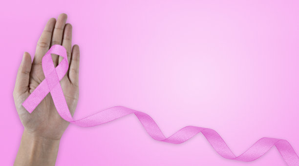 粉色乳腺癌关注丝带。手拿粉红丝带的背景。乳腺癌意识和十月粉红日，世界癌症日。图片下载