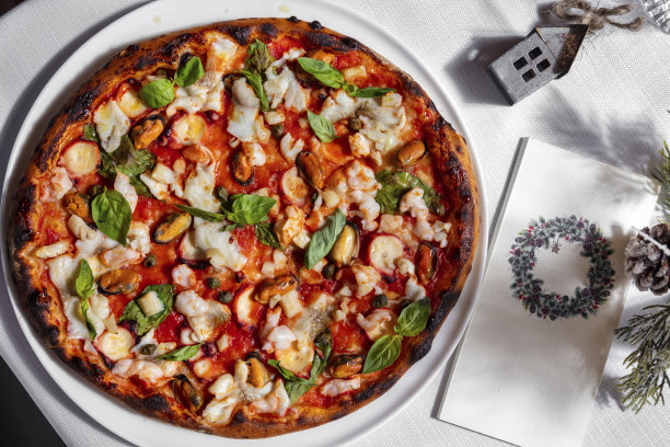 披萨配鱼，罗勒，虾，贻贝，番茄酱，鱿鱼奶酪和橄榄放在桌子上的盘子里图片下载