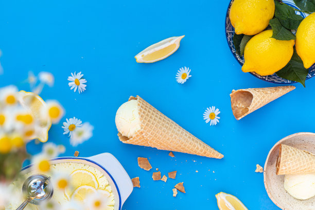 华夫饼甜筒和勺子与美味的自制柠檬冰淇淋放置在蓝色背景在白天的俯视图图片下载
