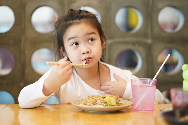 年轻的亚洲孩子喜欢用筷子吃日式烧饼图片下载