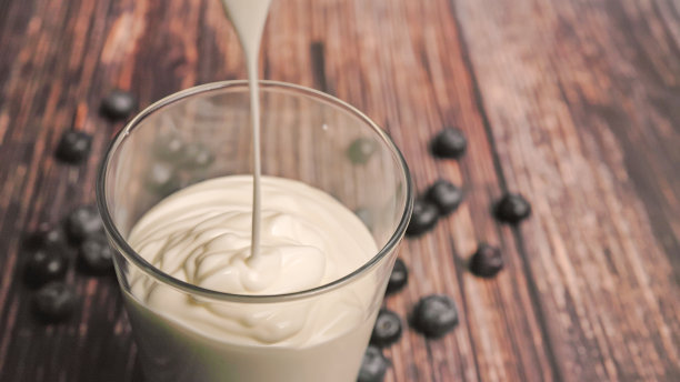 涓涓细流的酸奶流入玻璃杯，令人垂涎欲滴的酸奶是健康的一餐，是素食者的绝佳早餐。图片下载