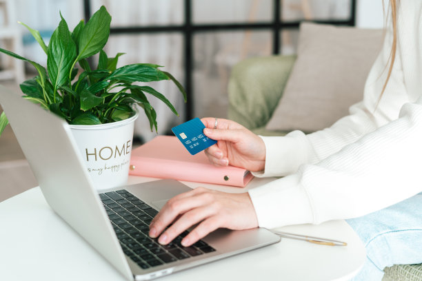 年轻女子坐在办公桌前，在笔记本电脑上使用借记卡进行网上购物和银行投资图片下载