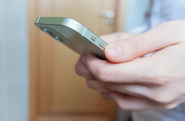 侧视图。男人或女人的手在家里的客厅里使用智能手机，打字，发短信或滚动新闻，购物。手的特写。高质量的水平照片。图片下载