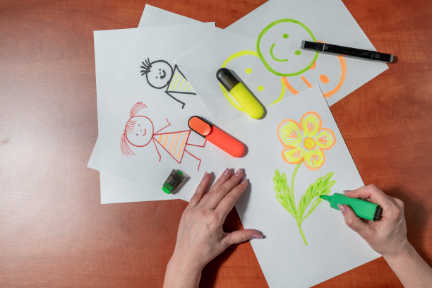 一个女人用毡尖笔在一张白纸上画着小男人。坐在桌子旁。从上面看图片下载