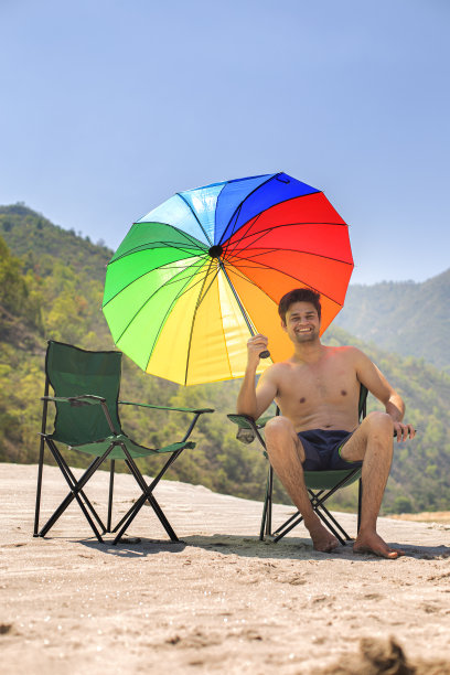 光膀子的男人坐在野营椅上，看着美丽的湖图片下载