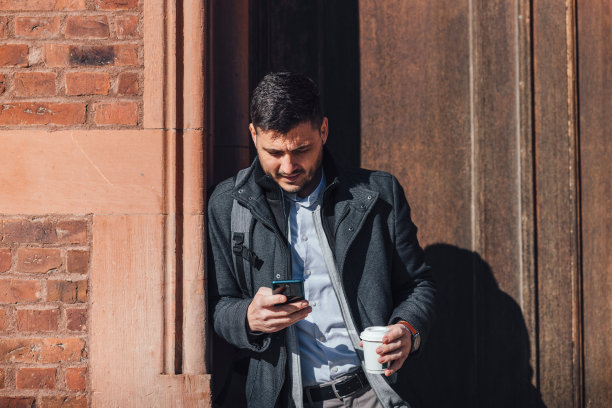 微笑的商人在城市里使用手机图片下载