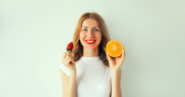 夏天，营养，饮食和素食的概念。快乐、健康、微笑的年轻女子拿着白色背景上的橙色水果片图片下载