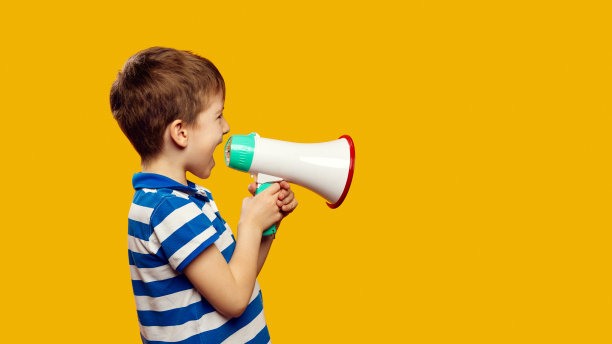 一个可爱的孩子的侧面肖像与扩音器在黄色背景与复制空间图片下载