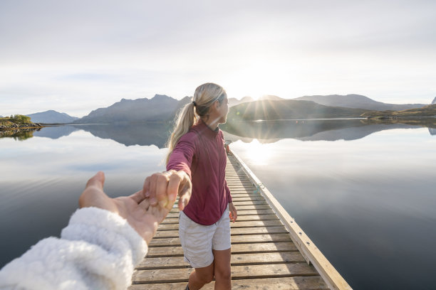 情侣在木制码头上，女孩牵着男友跟随的主观视角图片下载