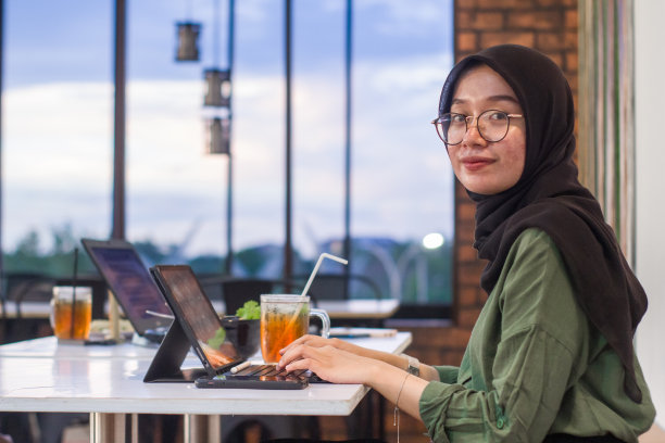 印度尼西亚年轻的穆斯林妇女坐在咖啡馆里使用数码平板电脑工作图片下载