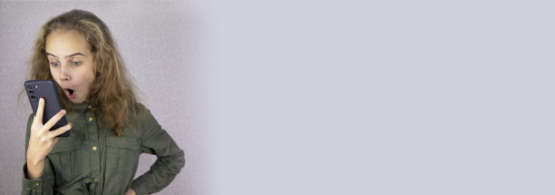 一个十几岁的女孩在打电话时感到惊讶和激动。使用智能手机与朋友和同学交流的概念图片下载