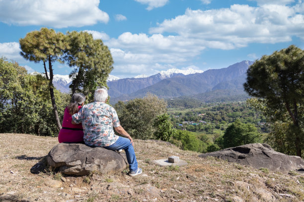 穿着运动服的人们坐在山谷之上，欣赏着全景。图片下载