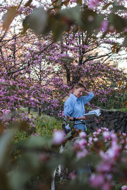 年轻貌美的女子在盛开的花园里读书图片下载