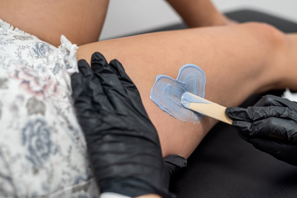 糖化师将蜡涂在客户的腿上，形成心形。图片下载