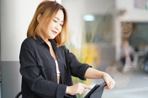 年轻的亚洲商业女性在咖啡馆使用电子平板电脑工作图片下载