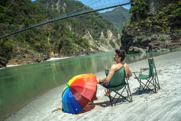 光膀子的男人坐在野营椅上，看着美丽的湖图片下载