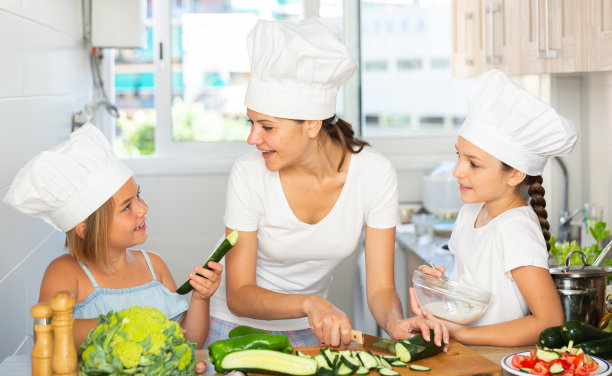 小妹妹和戴着帽子的妈妈学习做饭的照片图片下载