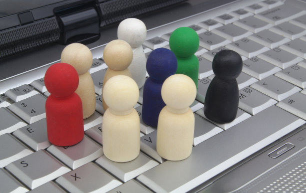 不同的木制人物在笔记本电脑键盘上。图片下载