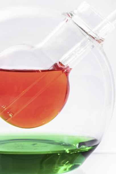 一个大的双层玻璃烧瓶立在白色的背景上。草莓糖浆倒在烧瓶的第一层，一根玻璃棒躺在上面。下层的绿色部分覆盖着糖浆。图片下载