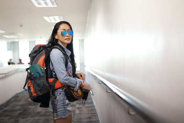 一名女游客背着背包查看航班时刻表，以确定起飞时间。单身女性旅行或背包客主题。后视图肖像。人工智能生成图片下载